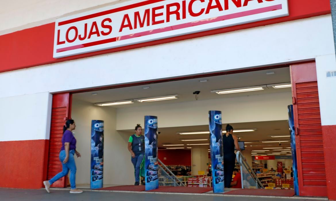 Fachada de uma loja Americanas, com clientes entrando e saindo.