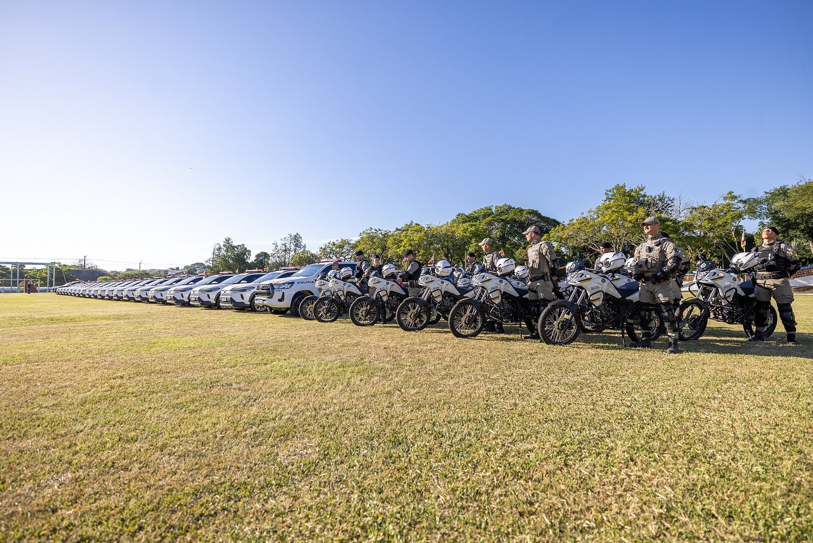 Viaturas e motocicletas da Brigada Militar enfileiradas durante solenidade de entrega de veículos.
