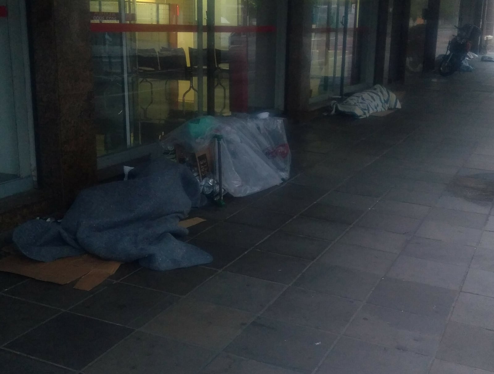 Pessoas em situação de rua dormem sobre cobertores e papelão em calçada de Porto Alegre (2020).