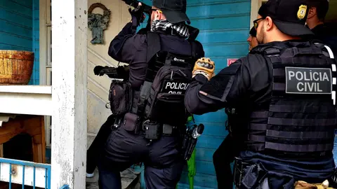 Policiais civis com coletes durante cumprimento de mandado de busca em operação de combate a golpes financeiros no Rio Grande