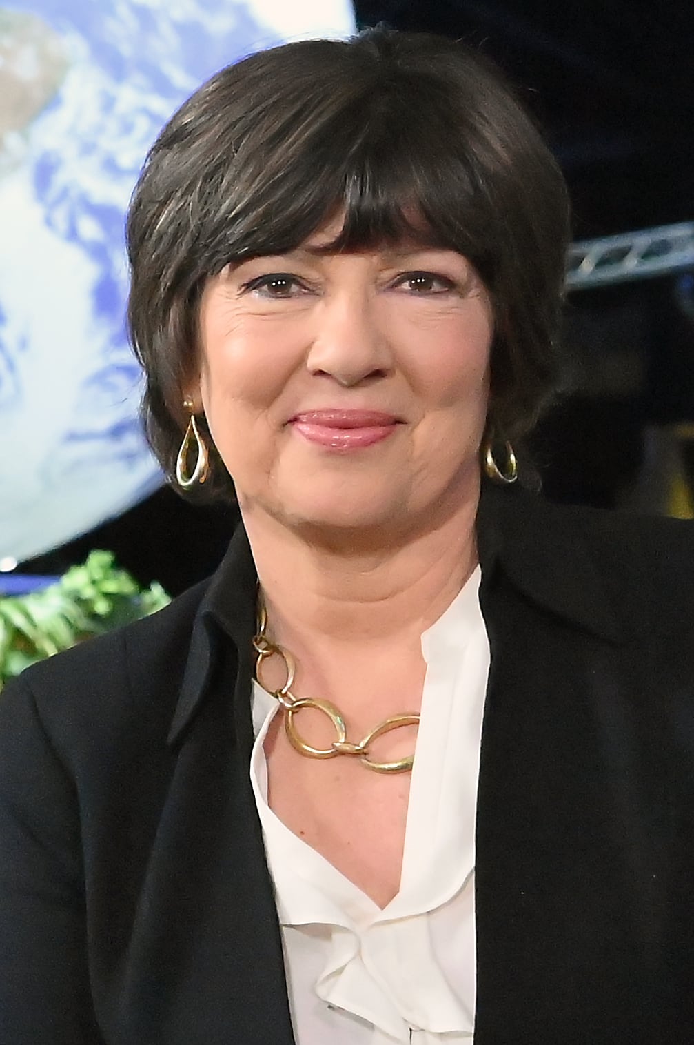 A jornalista Christiane Amanpour, em close, com um fundo azul que lembra o globo terrestre.