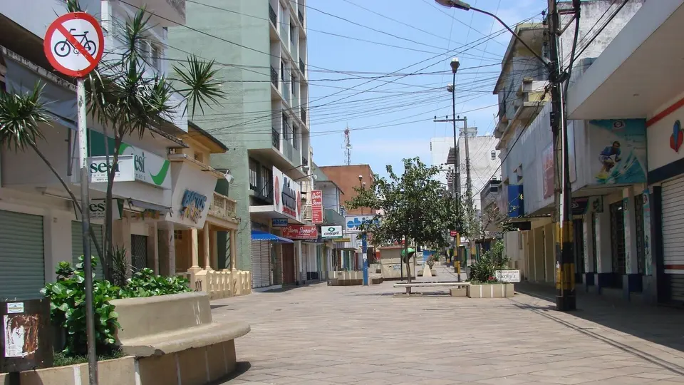 Calçadão do centro de Cruz Alta com lojas de portas fechadas e poucas pessoas caminhando, em dia de feriado