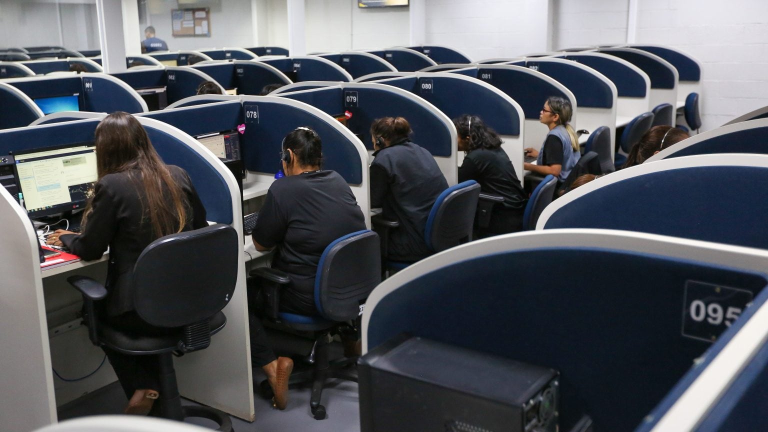 Atendentes trabalham em posto de atendimento telefônico (SAC). Decreto federal fixa atendimento humano das 8h às 20h.