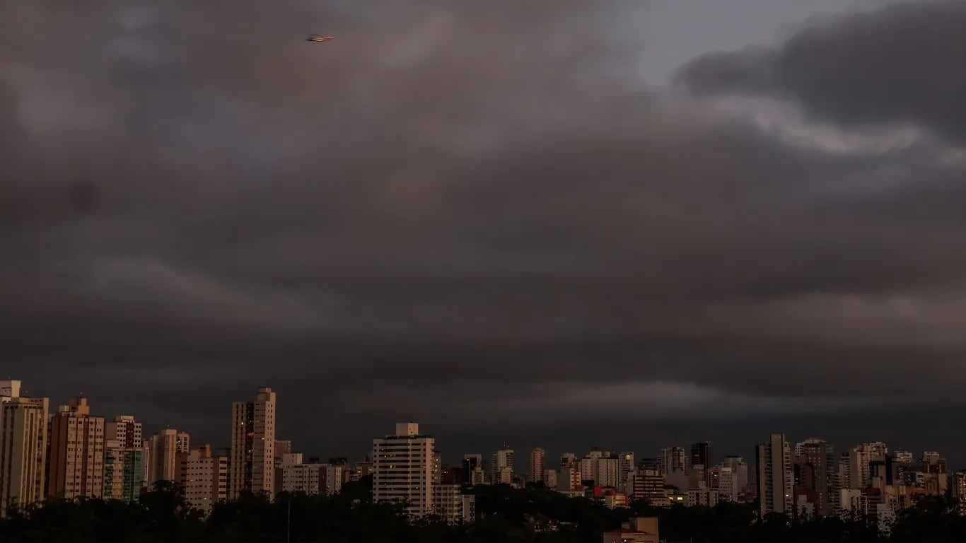 Raios iluminam o céu durante temporal sobre área urbana.
