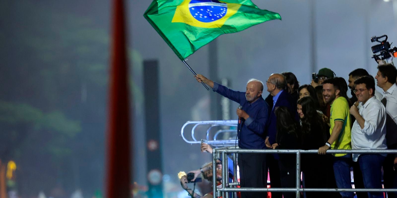 Lula acena com a bandeira do Brasil durante ato público.