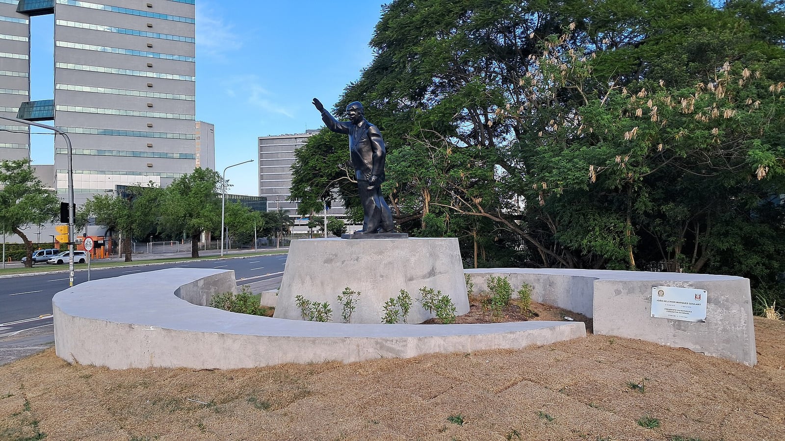 Monumento a João Goulart em Porto Alegre, com a estátua do ex-presidente sobre base de concreto em canteiro às margens de uma avenida.