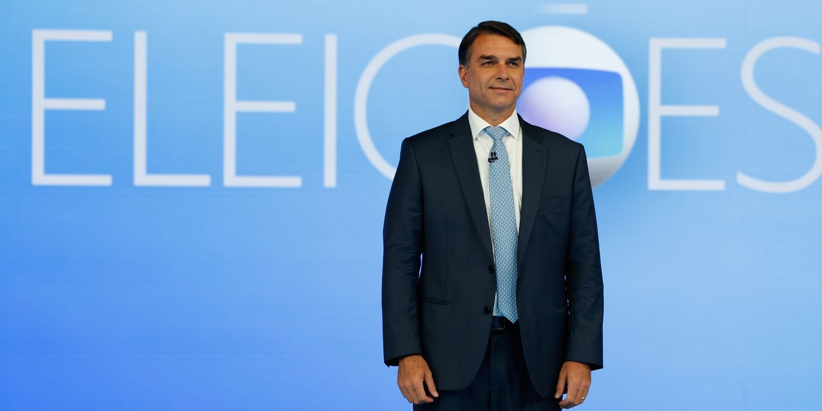 O senador Flávio Bolsonaro diante do painel de cobertura eleitoral da Globo. Ele afirmou acreditar na inocência do policial militar acusado de matar a menina Ana Clara, de 5 anos.