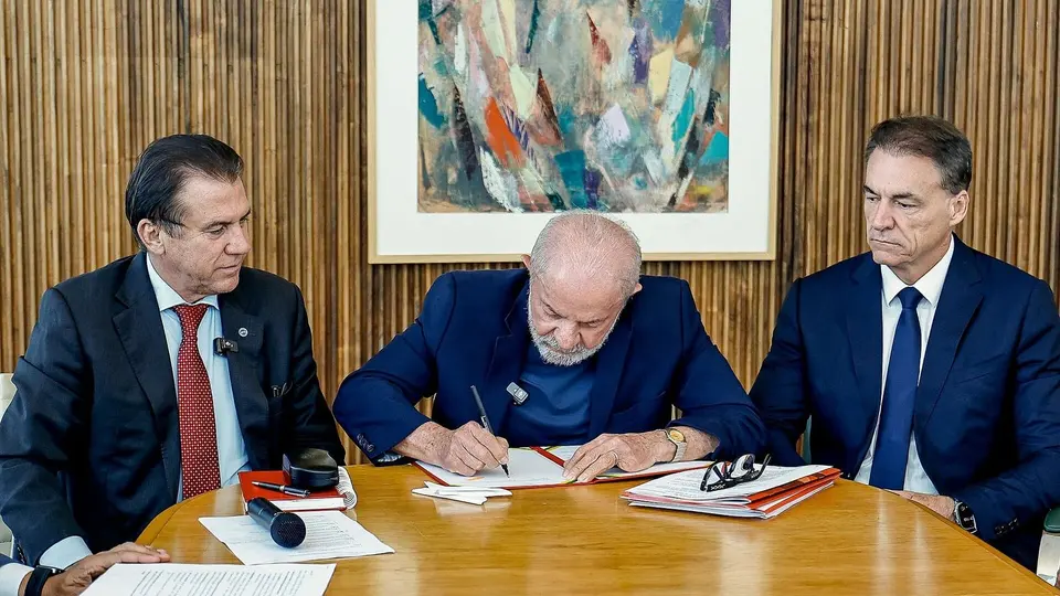 Presidente Lula assina documento em mesa com caneta, em cerimônia oficial de regulamentação do PAT em Brasília