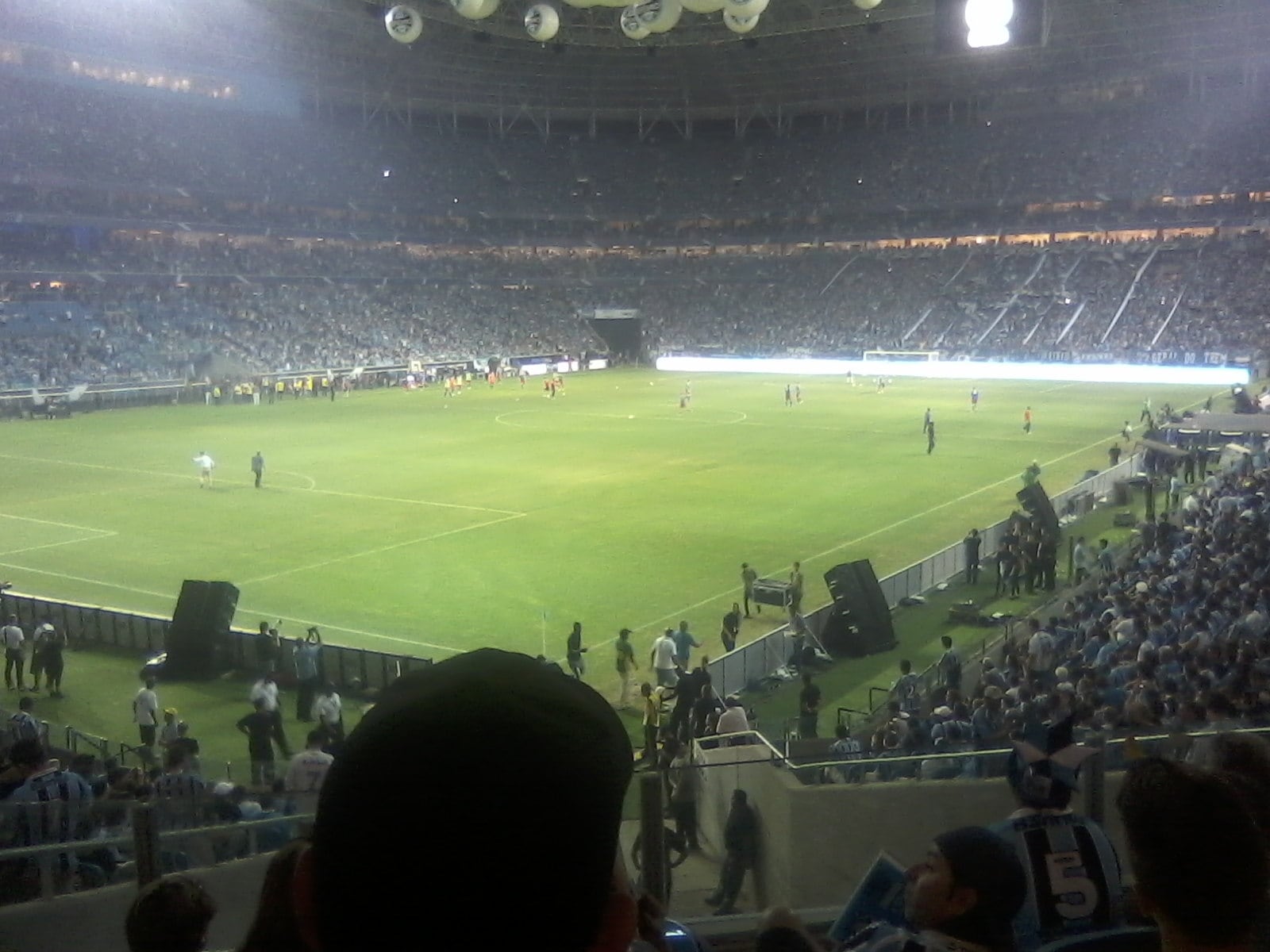 Vista da Arena do Grêmio durante uma partida, com torcedores nas arquibancadas.