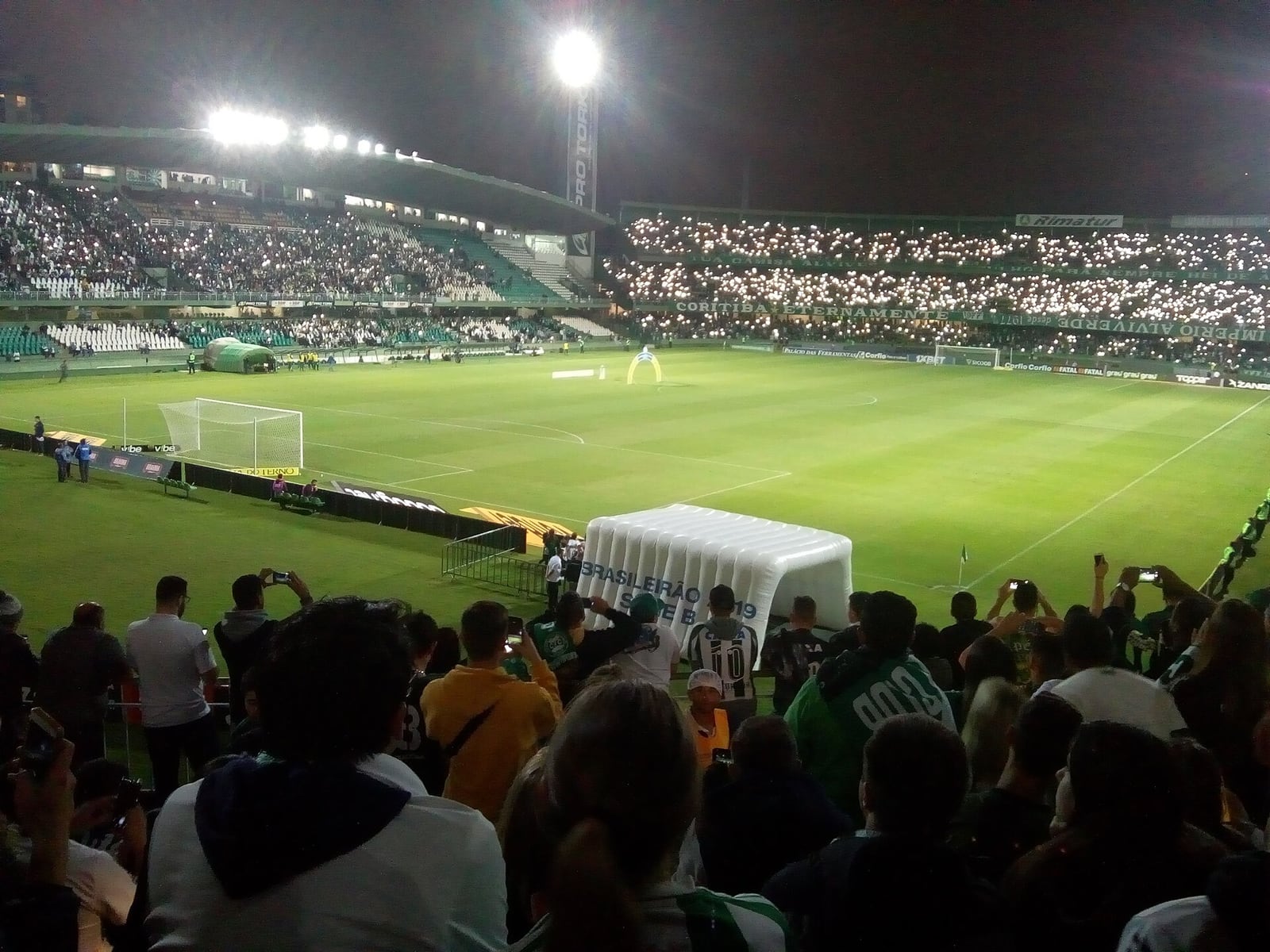 Vista do Estádio Couto Pereira, em Curitiba, durante partida noturna com torcida nas arquibancadas.