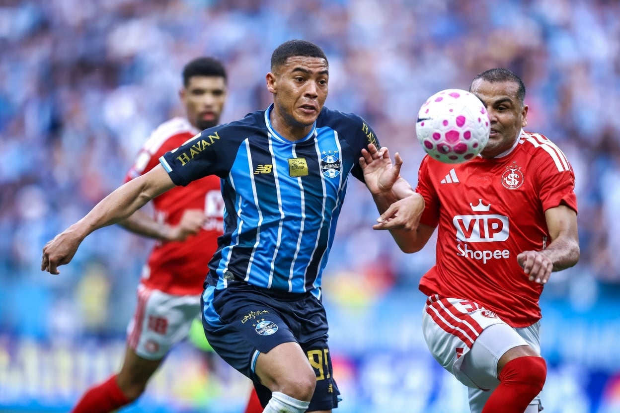 Jogadores do Grêmio (azul) e do Internacional (vermelho) disputam a bola durante uma partida.