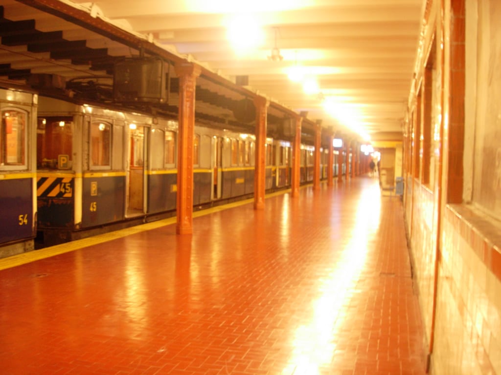 Plataforma vazia de uma estação do Subte de Buenos Aires, com um trem antigo estacionado ao lado.