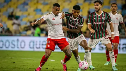 Jogadores do Inter e do Fluminense disputam a bola em partida entre as equipes.