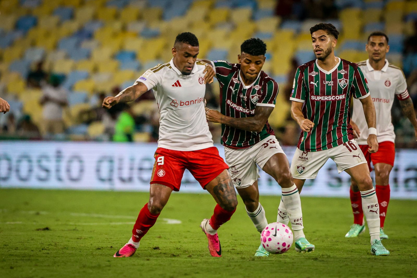 Jogadores do Inter e do Fluminense disputam a bola em partida entre as equipes.