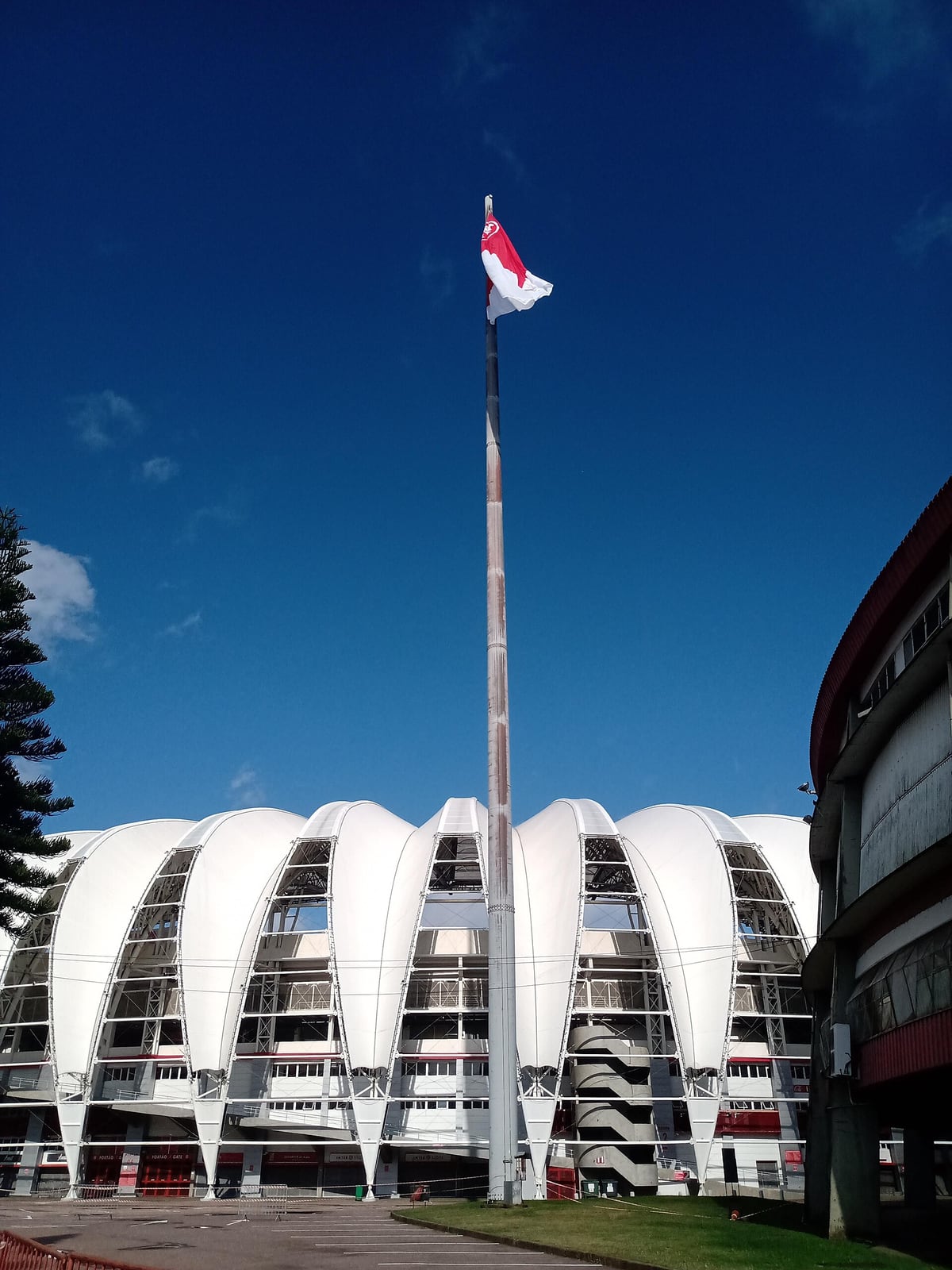 Vista externa do Estádio Beira-Rio, em Porto Alegre, com bandeira hasteada em mastro.