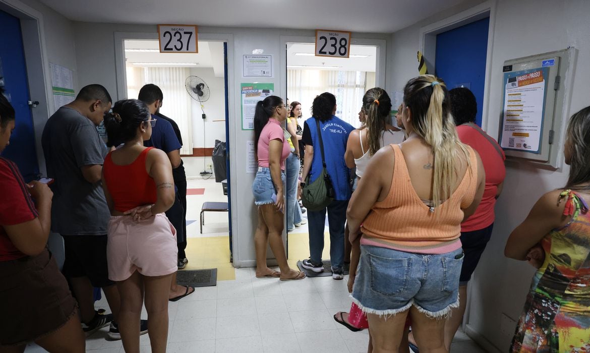 Eleitores formam fila em corredor de local de votação, com placas indicando as seções 237 e 238.
