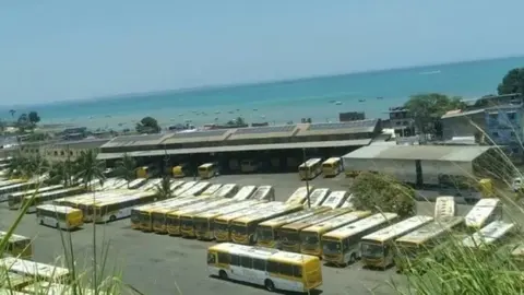 Ônibus estacionados em garagem à beira-mar, na discussão sobre o transporte coletivo em Salvador.
