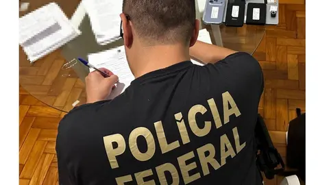 Agente da Polícia Federal analisa documentos e equipamentos durante a operação que apura prejuízo em previdência de São Roque