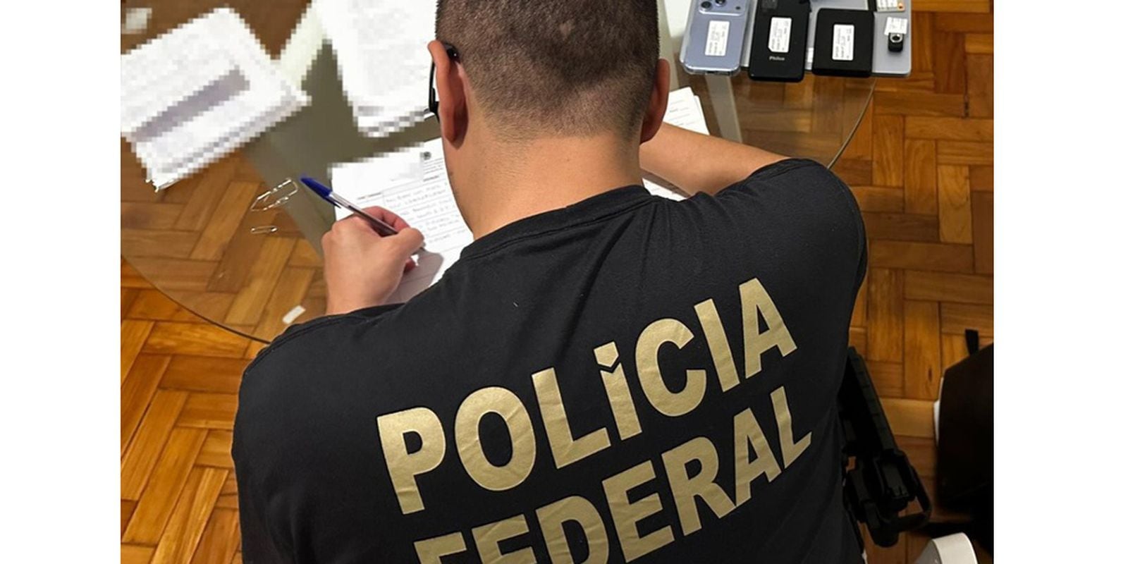 Agente da Polícia Federal analisa documentos e equipamentos durante a operação que apura prejuízo em previdência de São Roque (SP).
