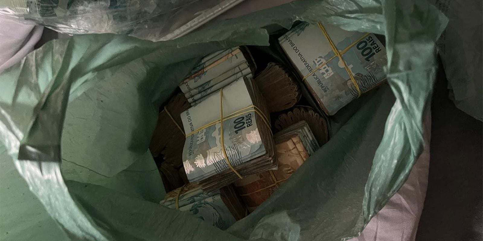 Dinheiro em espécie apreendido em sacola plástica durante a operação da Polícia Federal.