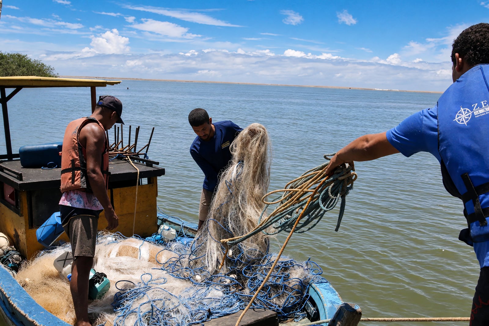 Pescadores recolhem redes de uma embarcação; a portaria retoma a pesca em faixa da foz do Rio Doce, no ES. Foto de divulgação oficial.