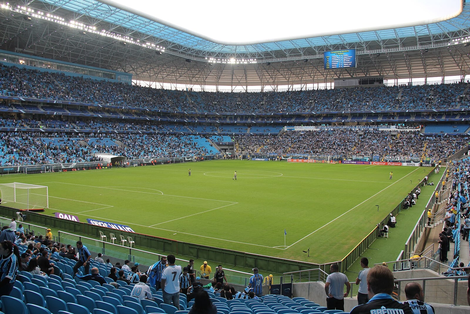 Vista geral da Arena do Grêmio, em Porto Alegre, com arquibancadas ocupadas durante uma partida.