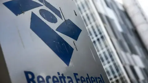 Prédio comercial com fachada de vidro e movimento de pedestres na calçada, em dia claro na cidade