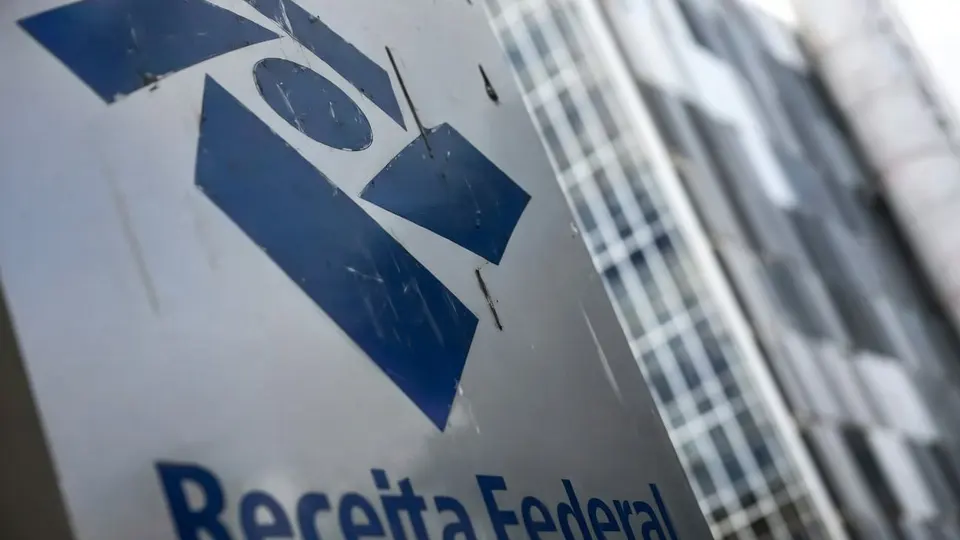 Prédio comercial com fachada de vidro e movimento de pedestres na calçada, em dia claro na cidade