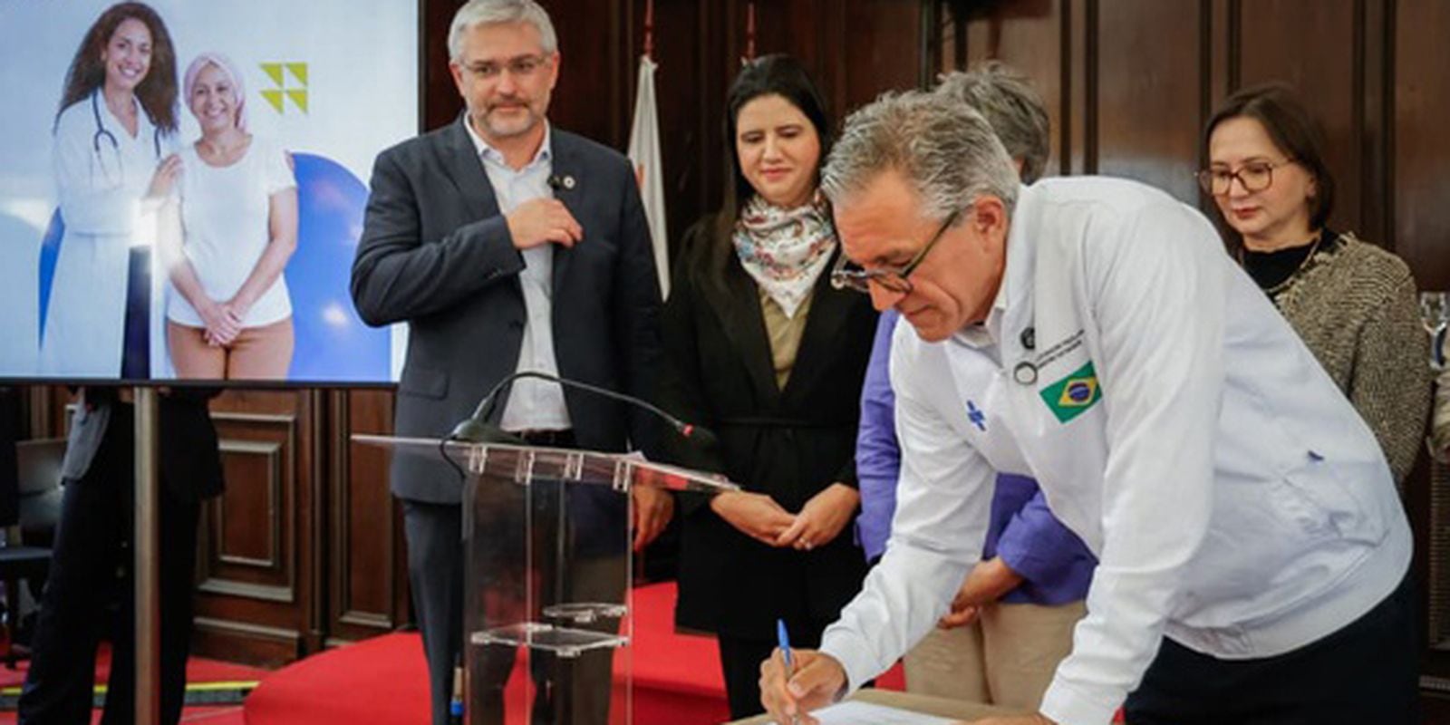 Representante do Ministério da Saúde assina documento durante cerimônia de início da oferta de novos medicamentos oncológicos no SUS.